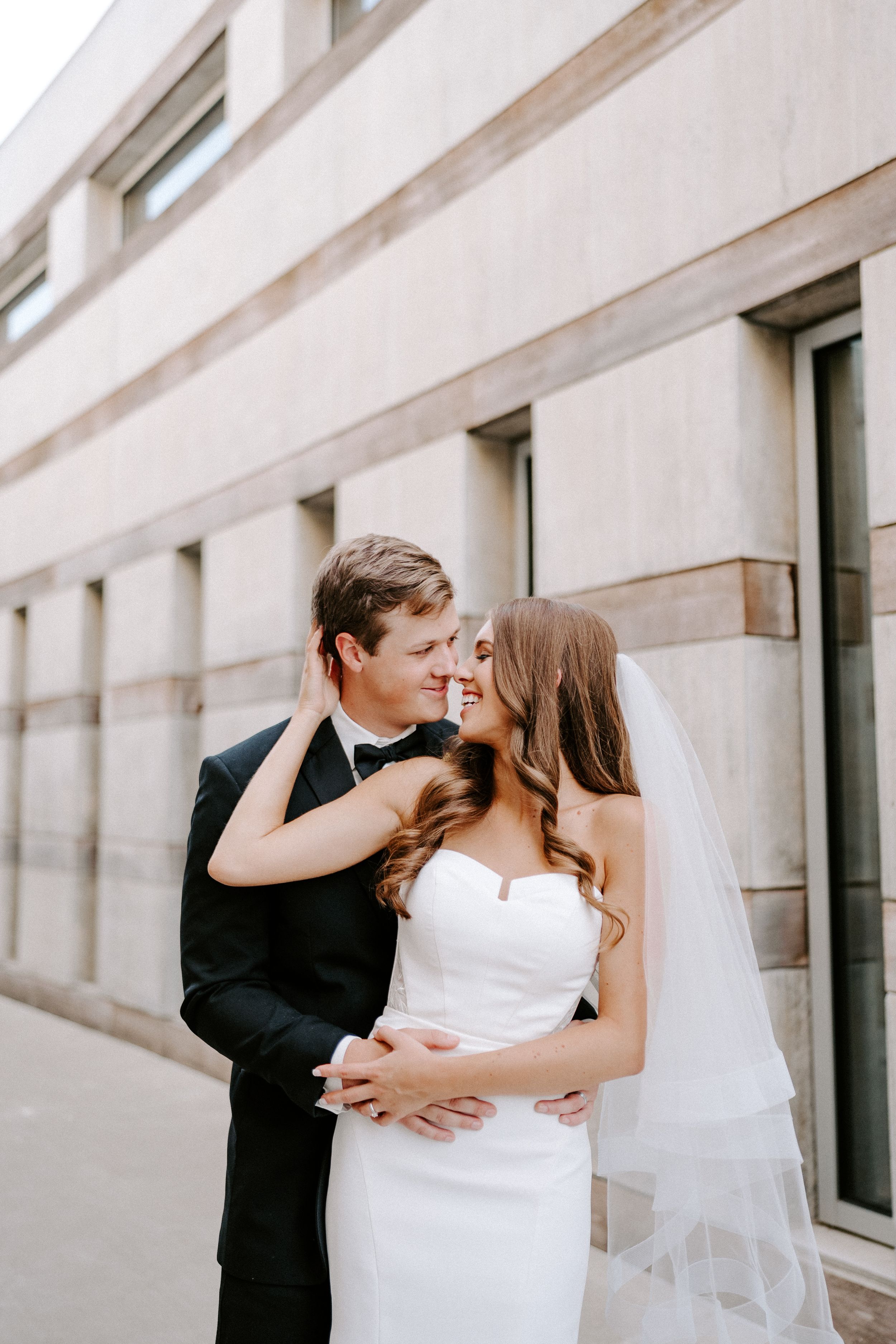 A romantic sequence of wedding photos showing a couple embracing and kissing against a modern architectural backdrop.