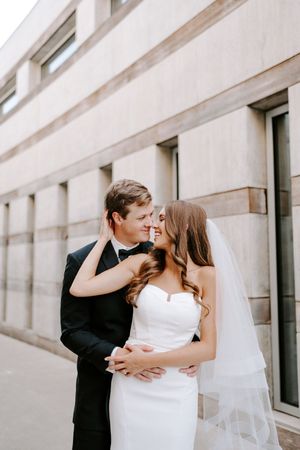 A romantic sequence of wedding photos showing a couple embracing and kissing against a modern architectural backdrop.