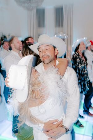 A romantic dip dance move on a wedding dance floor with blue lighting and guests in the background.