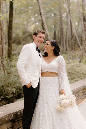 A happy couple shares romantic moments on a wooden walkway in a forest setting during their wedding day.