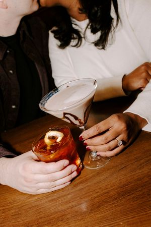 A sequence of hands holding a drink on a wooden table showing the progression of consuming a beverage.