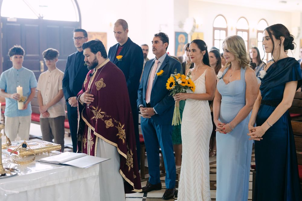 Wedding guests gather in a line at an elegant reception venue, holding drinks and mingling during cocktail hour.