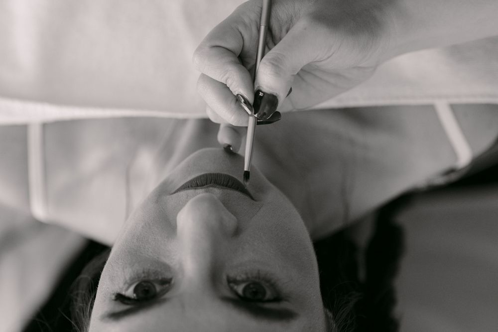 Black and white close-up photo of someone applying lipstick in an upside down perspective.