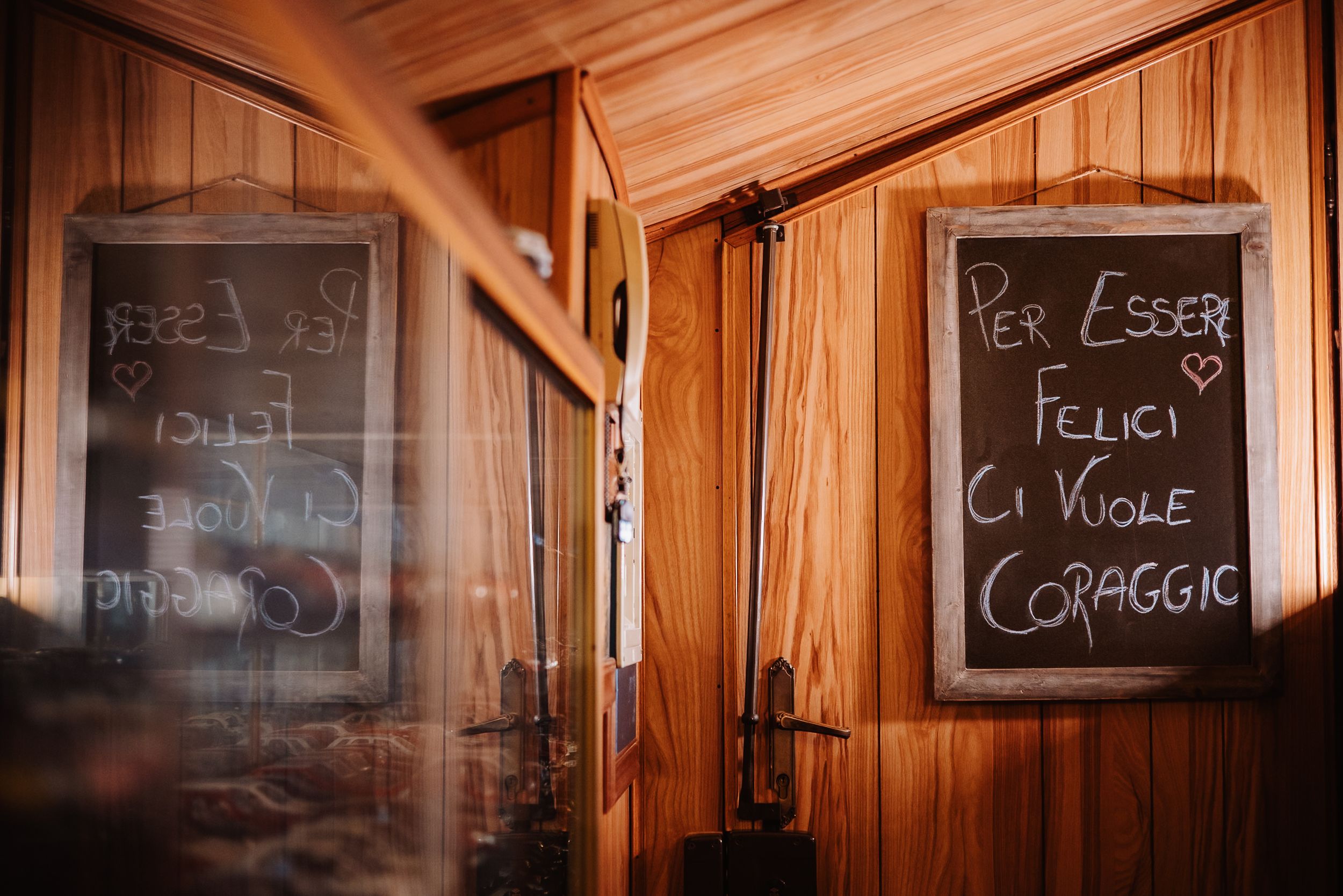 A row of dark chalkboards mounted on wooden paneled walls displays handwritten text and menu items.