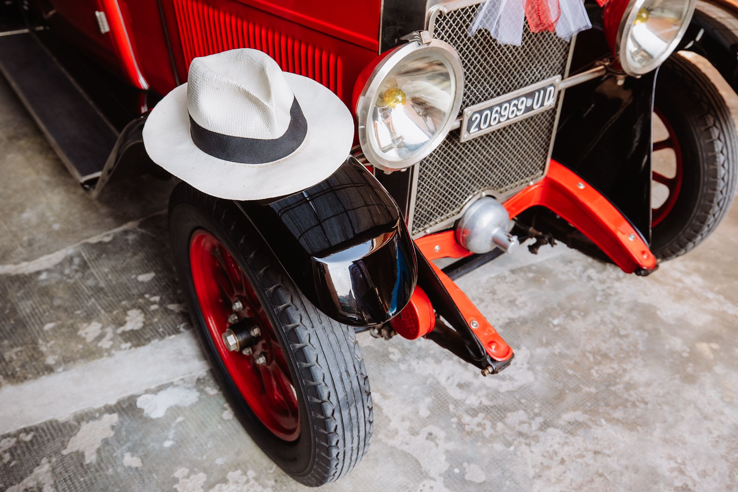 A close-up view of vintage red tractor wheels and mechanical components on a concrete surface.