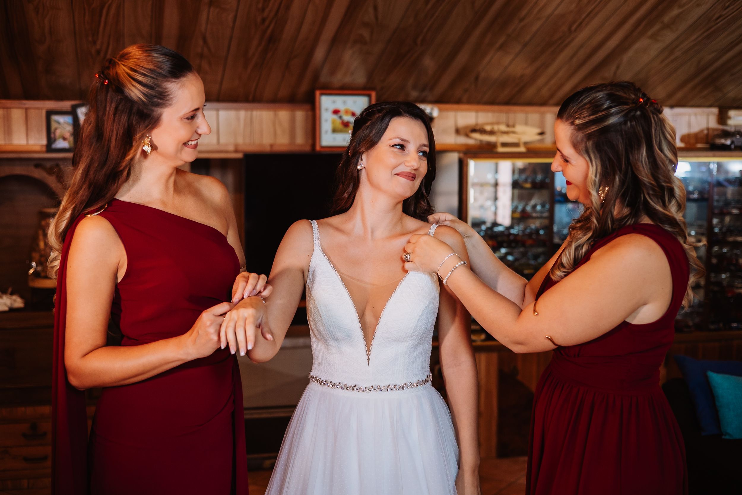 A group in burgundy and white formal attire share an emotional moment during a wedding celebration.