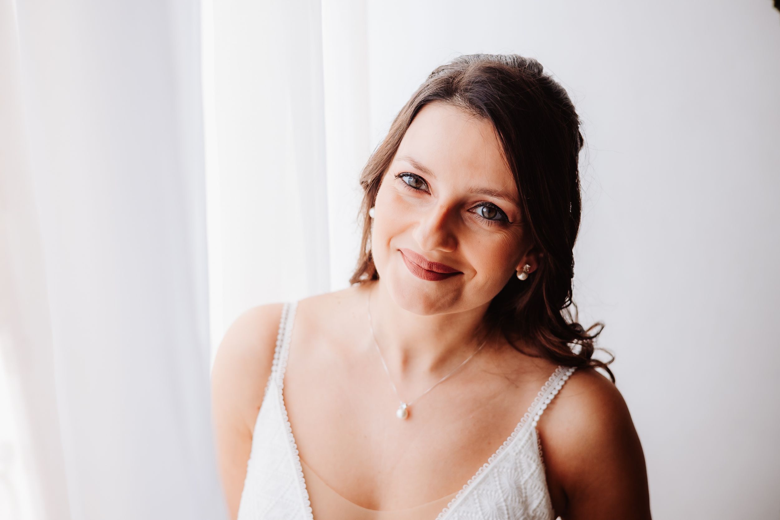 Woman in white lingerie poses gracefully against light background in romantic boudoir photoshoot.