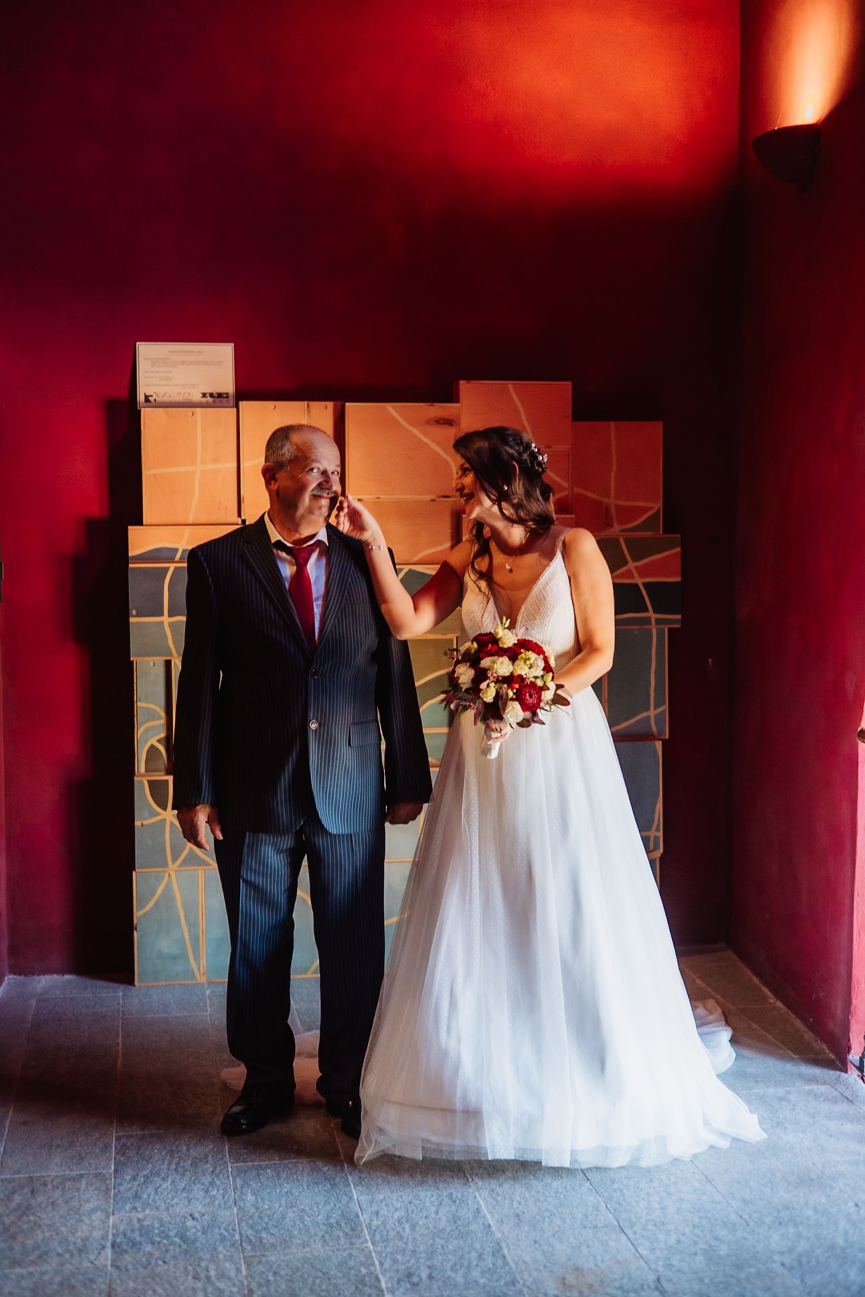 A series of wedding photos showing a bride in a white gown with someone in formal attire against a deep red wall.
