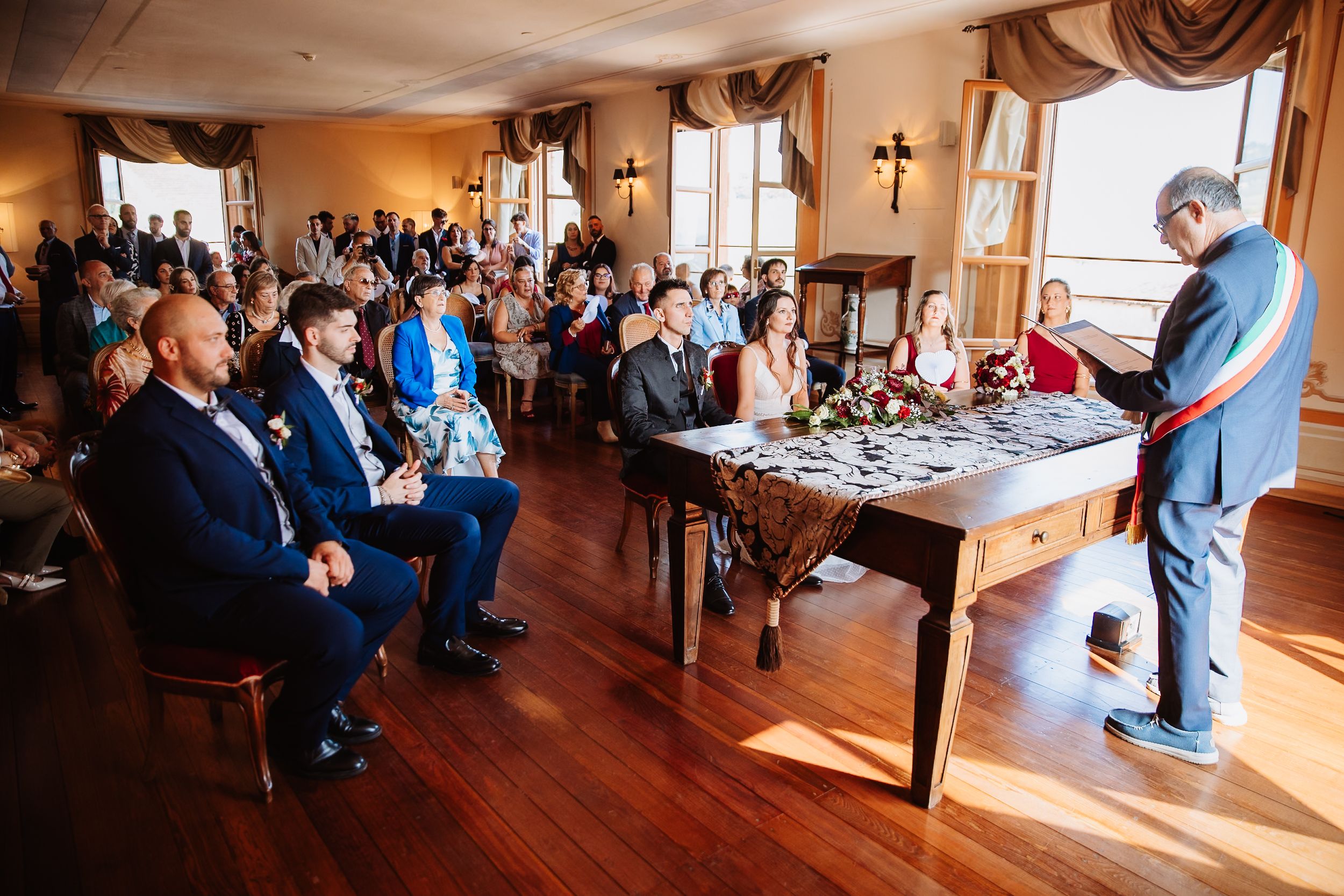 Panoramic view of a wedding ceremony and reception venue with elegant decor and wooden floors.