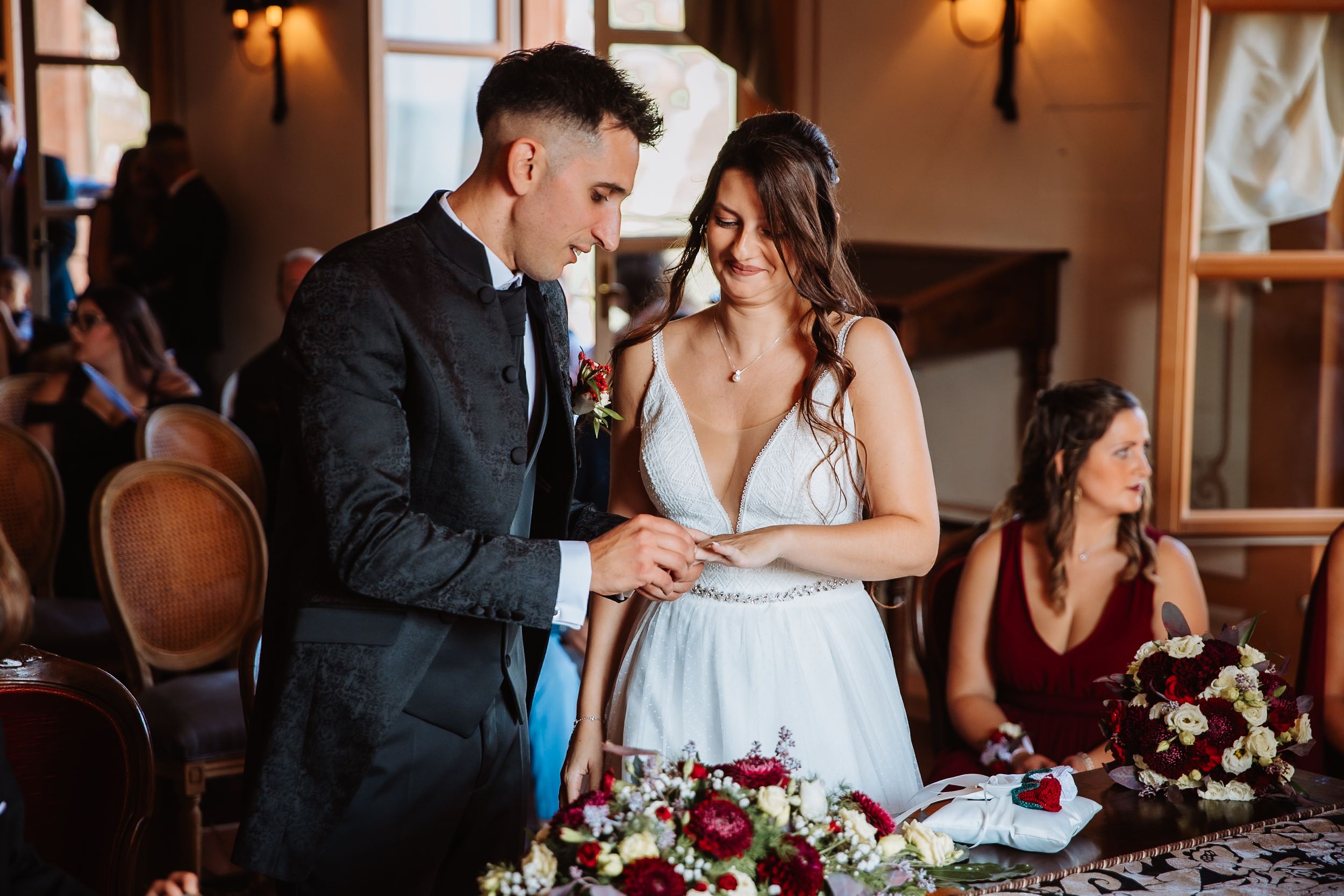 Elegant couple sharing an intimate moment at their wedding reception with burgundy floral table decor.
