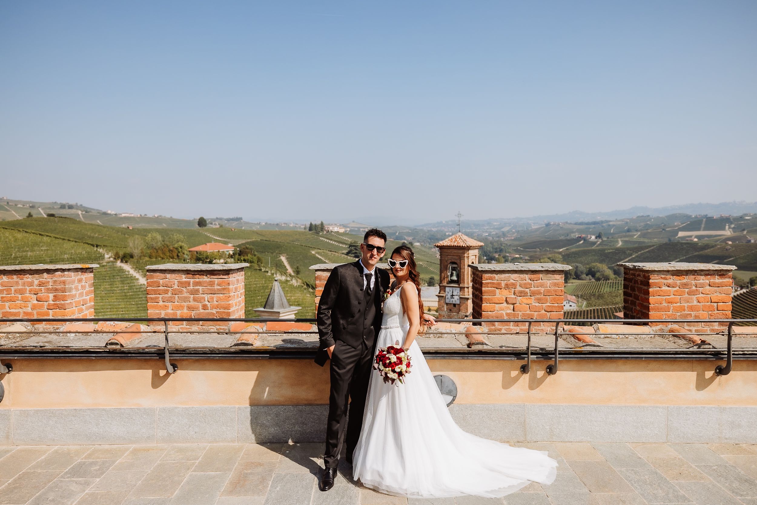 A scenic panoramic view of rolling hills and mountains with a rustic brick structure in the foreground.