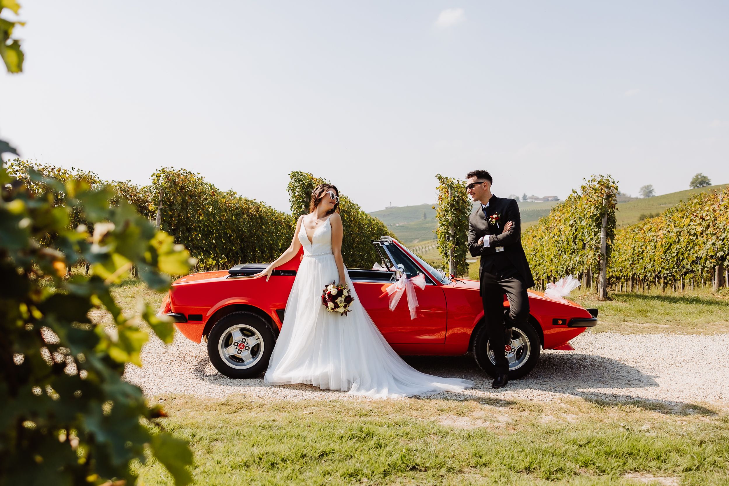 A collection of wedding photos featuring a classic red car in a vineyard setting with elegant wedding attire and poses.