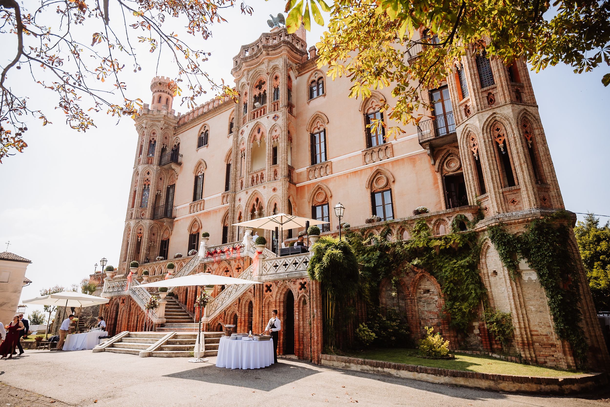 A panoramic view of a grand historic mansion exterior with elegant stone architecture and autumn trees.
