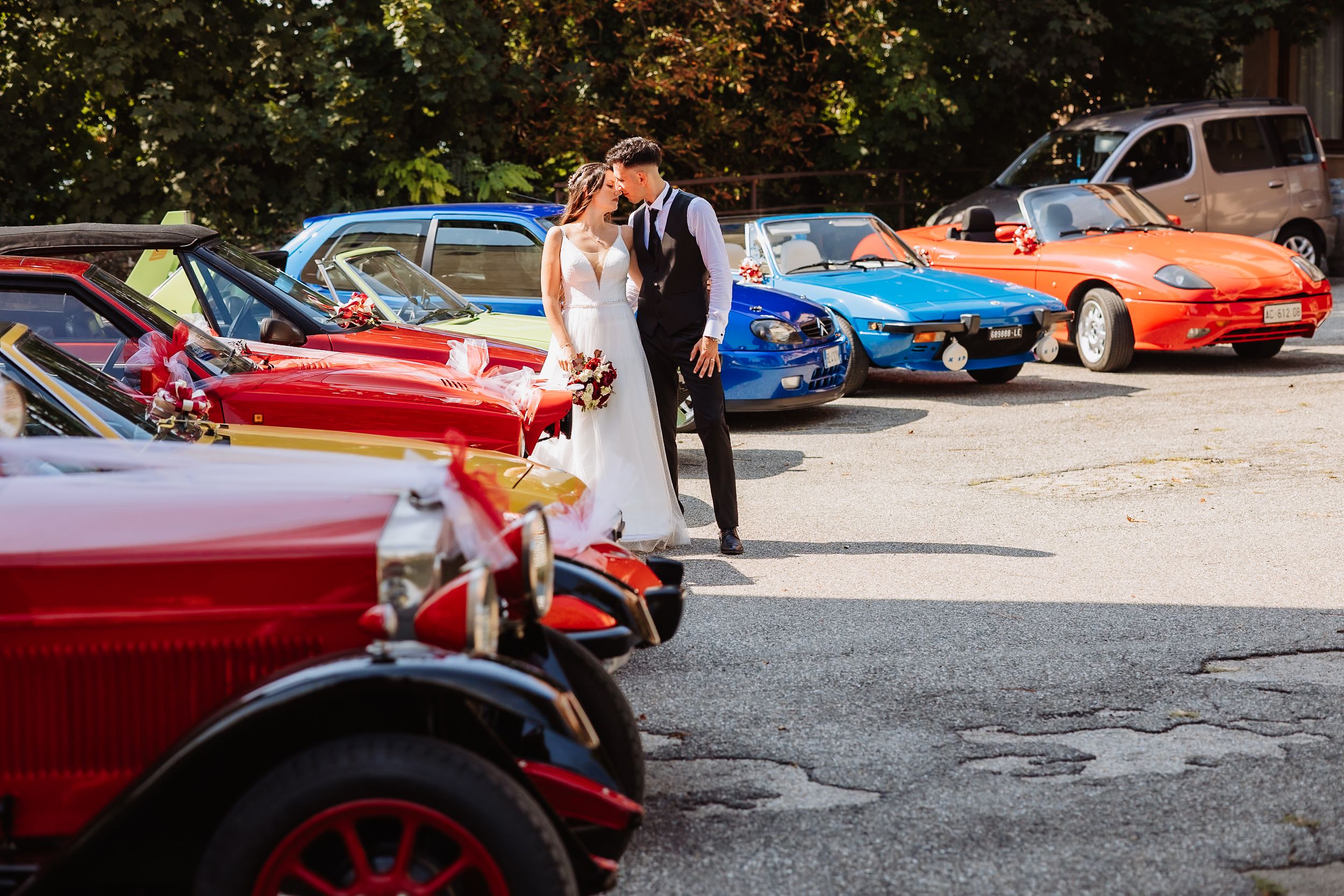 Classic red sports cars lined up at an outdoor car show event on a sunny day.