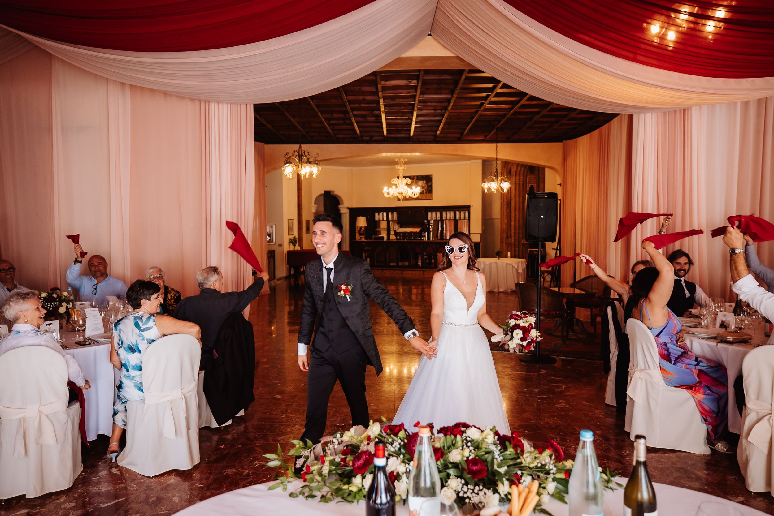 Wedding reception venue decorated with elegant white drapes and warm lighting for an evening celebration.