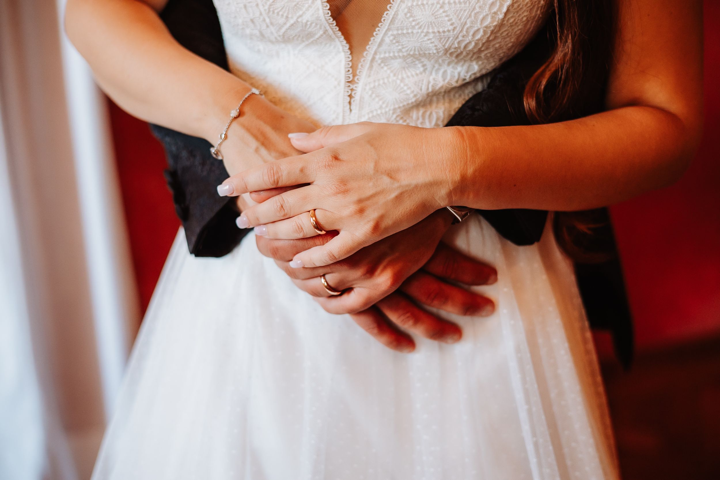 A close-up view of hands holding a wedding ring during a traditional ceremony with red and white decor.