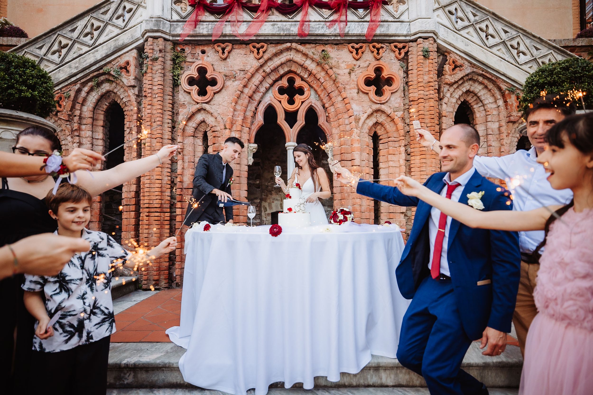 Guests throw rose petals during a joyful celebration outside a Gothic-style brick church.