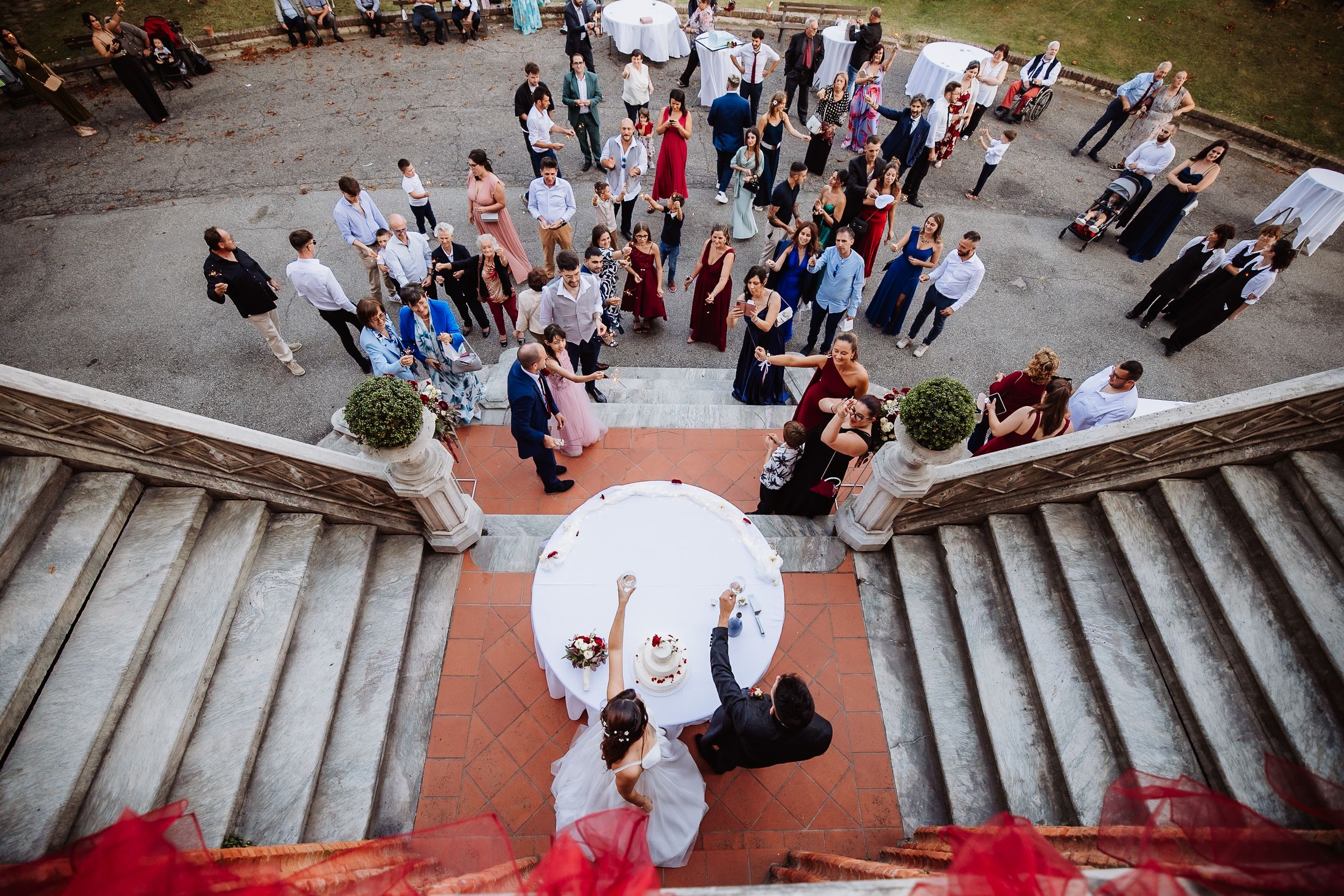 Aerial view of wedding guests gathered at bottom of grand stone staircase during outdoor ceremony.