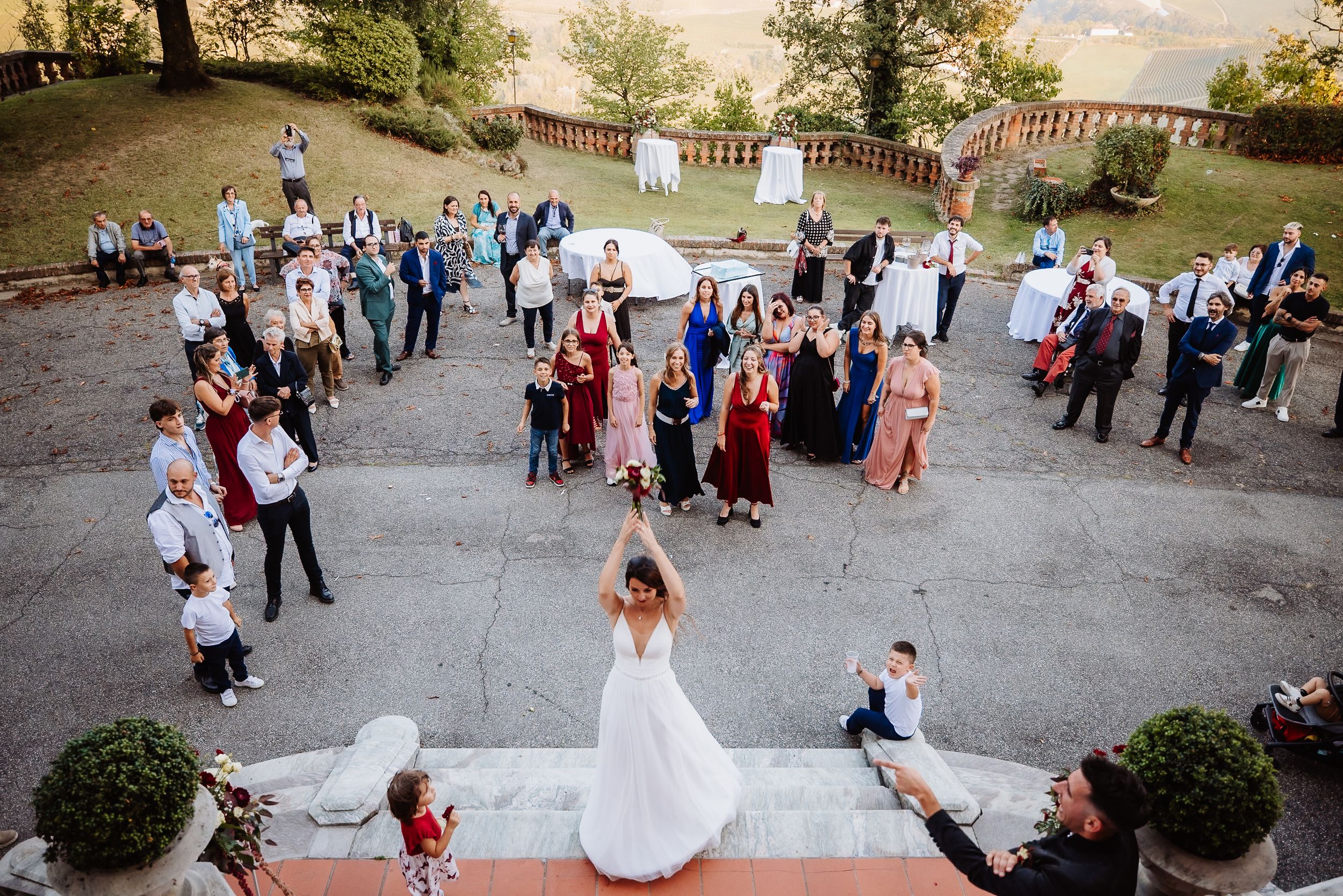 Aerial view of a wedding celebration on an outdoor terrace with guests gathered around stone steps and decorative planters.