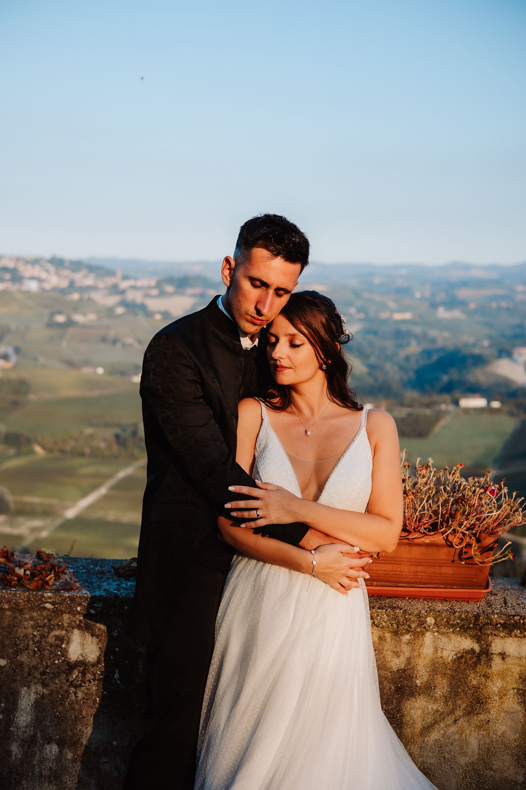 Romantic sunset wedding photos captured against a scenic Italian vineyard landscape with rolling hills in the background.