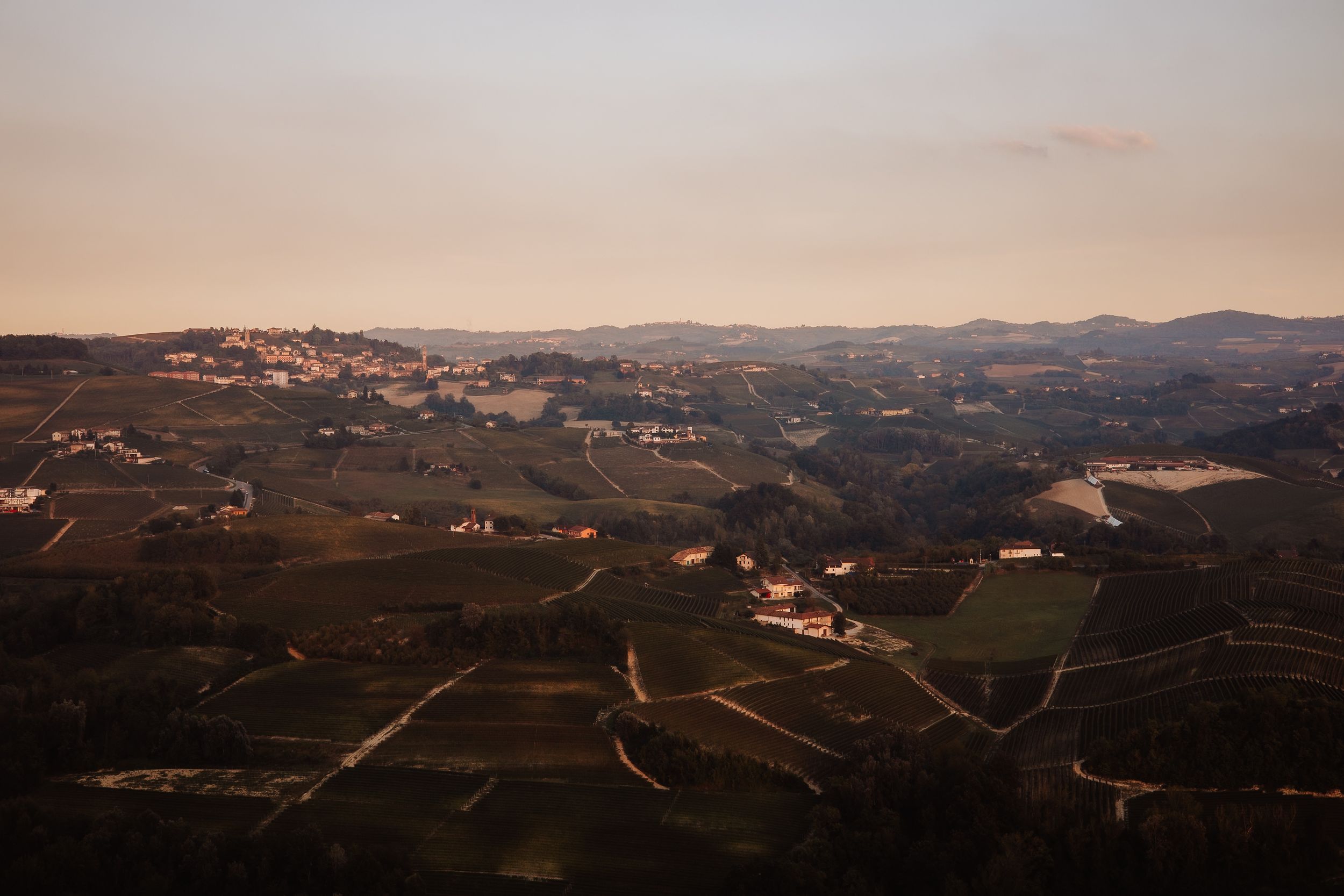 Panoramic view of rolling hills with vineyards and scattered buildings in the Douro Valley at sunset.