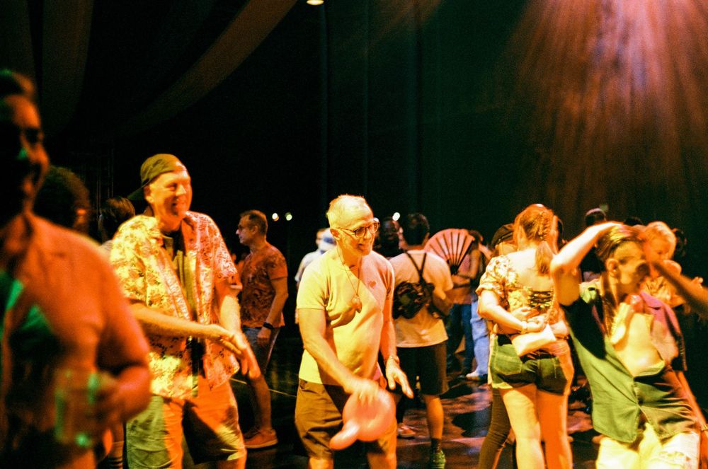 Energetic crowd dancing and moving together at a lively nightclub event under colorful lighting.