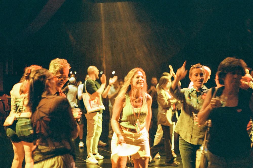 Crowd of party-goers dancing under dramatic spotlights in a nightclub setting.