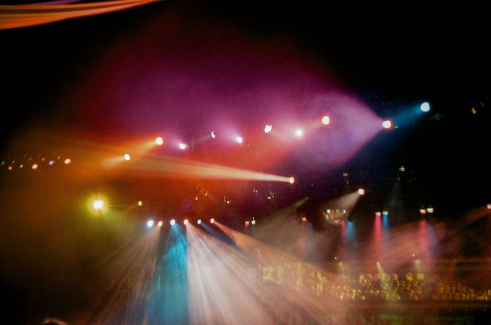 Dramatic stage lighting creates colorful silhouettes of performers during a theatrical production.