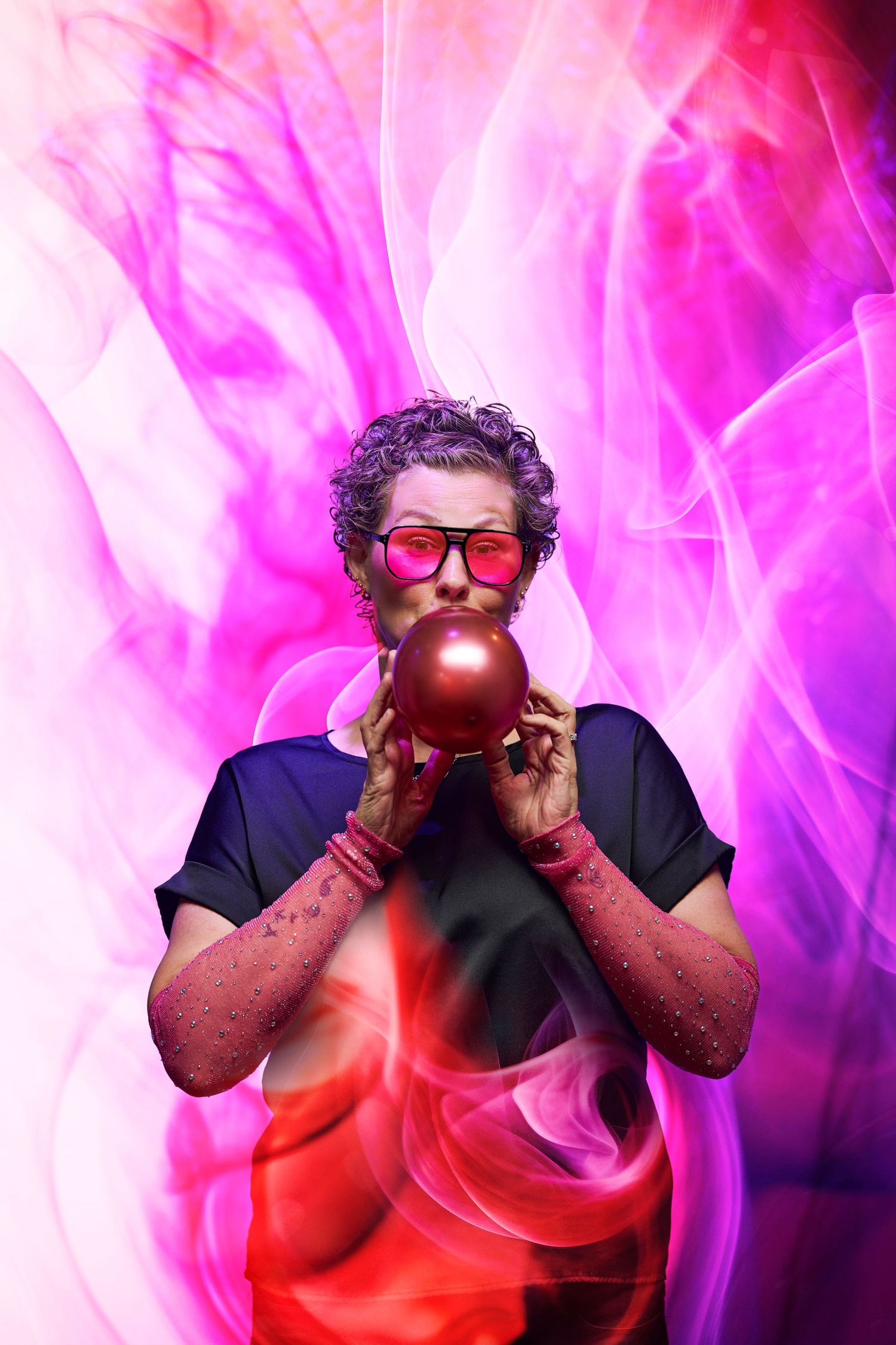 Figure in red sunglasses blowing bubblegum against vibrant pink and magenta smoke effect background.