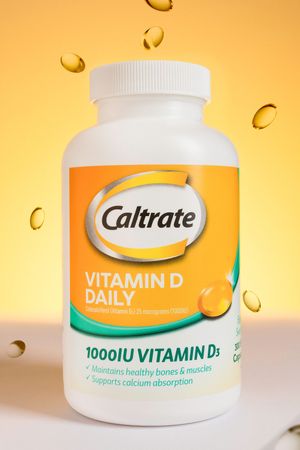 Caltrate Vitamin D3 supplement bottles and soft gel capsules displayed against an orange glow background.