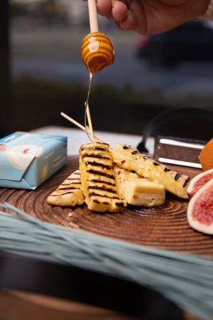 Honey drizzling in thin streams over stacked cookies on a turquoise and brown ceramic plate.