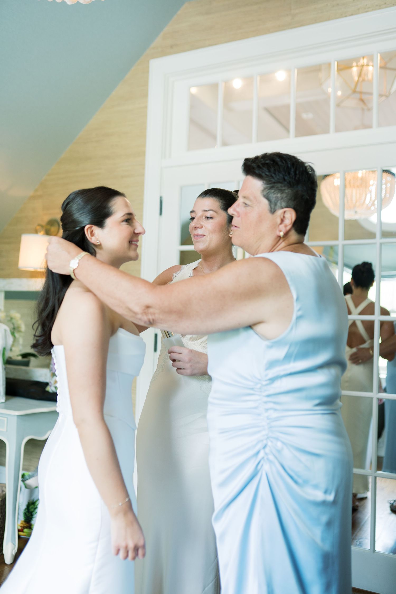 Wedding party members in light blue dresses share joyful embraces.