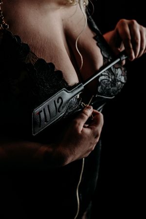 Close-up dark moody shot of hands adjusting black lace lingerie with detailed embroidery. Grand Rapids Boudoir Photography Intimate Sessions