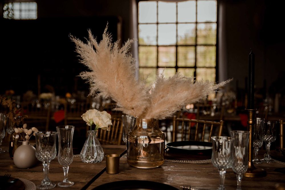 Bohemian fall wedding décor with rust orange and black accents, pampas grass, dried floral centerpieces, and warm candlelight