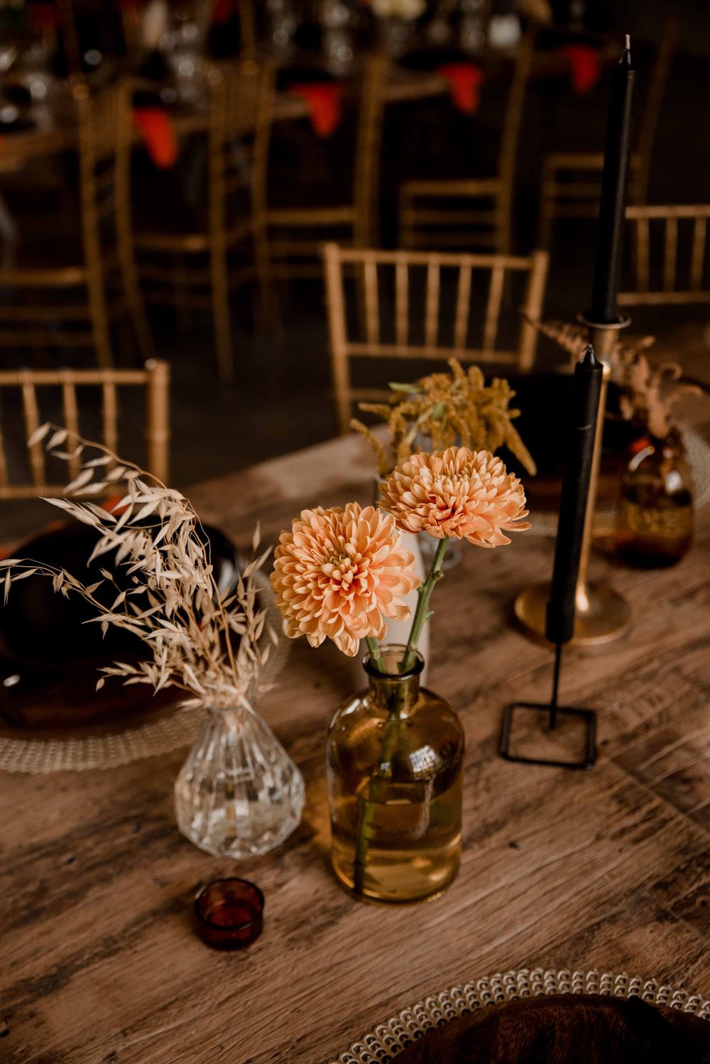 Bohemian fall wedding décor with rust orange and black accents, pampas grass, dried floral centerpieces, and warm candlelight