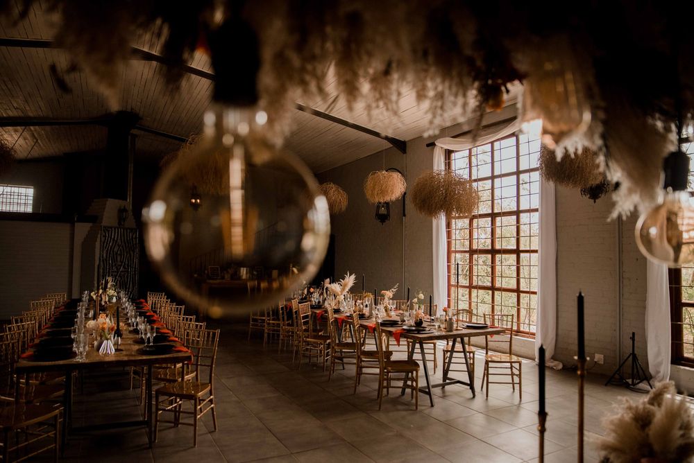 Bohemian fall wedding décor with rust orange and black accents, pampas grass, dried floral centerpieces, and warm candlelight