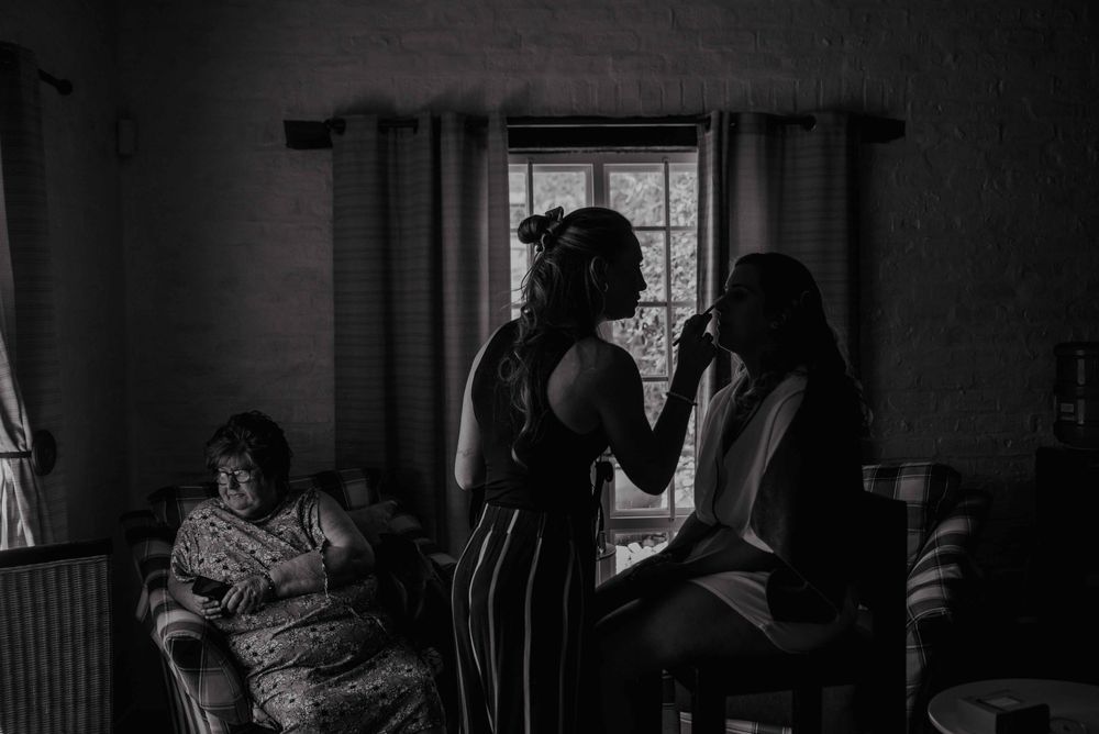 Moody black and white photo of the bride getting her make up done before het wedding ceremony