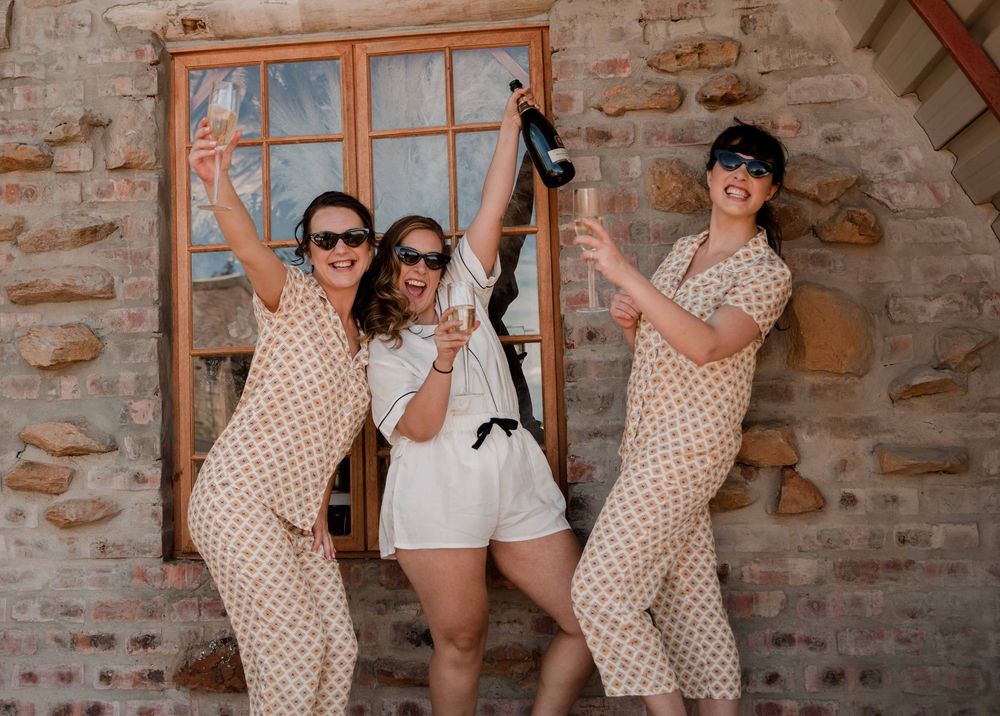 Bride and Bridesmaids laughing joyfully as the bride pops the champagne in their cute little wedding pajamas