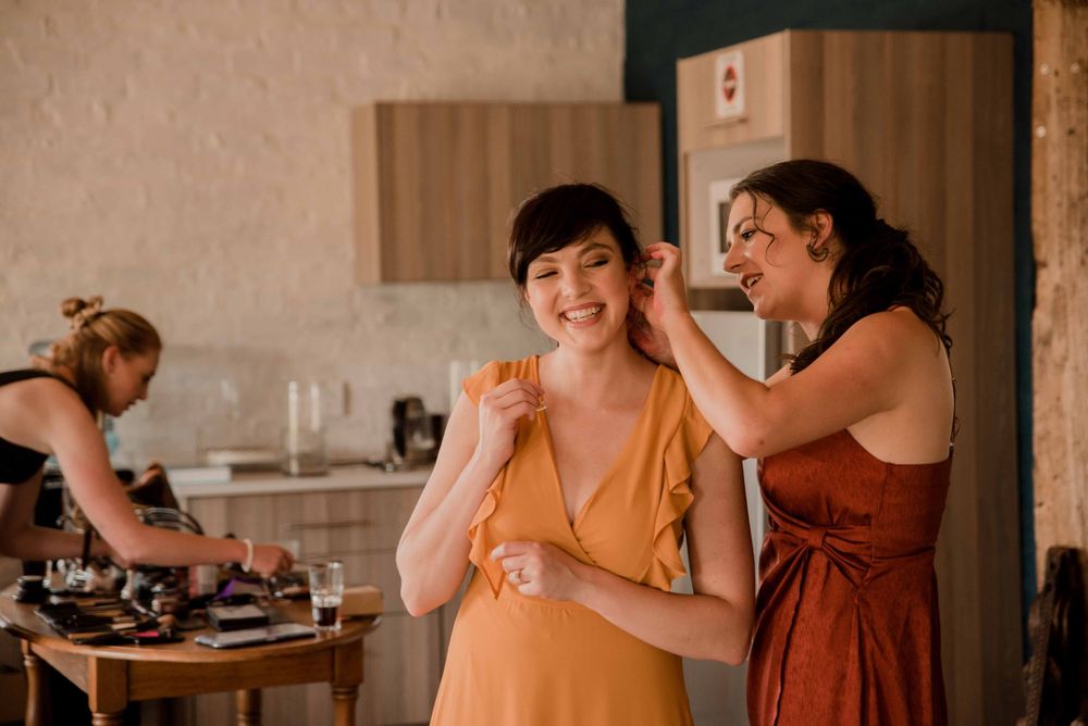 The Bridesmaids in their elegant dresses helping each other with the last finishing touches.