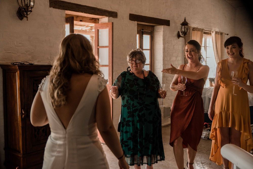 The bridesmaids and the mother of the bride's joyful faces as they see the bride in her wedding dress for the first time