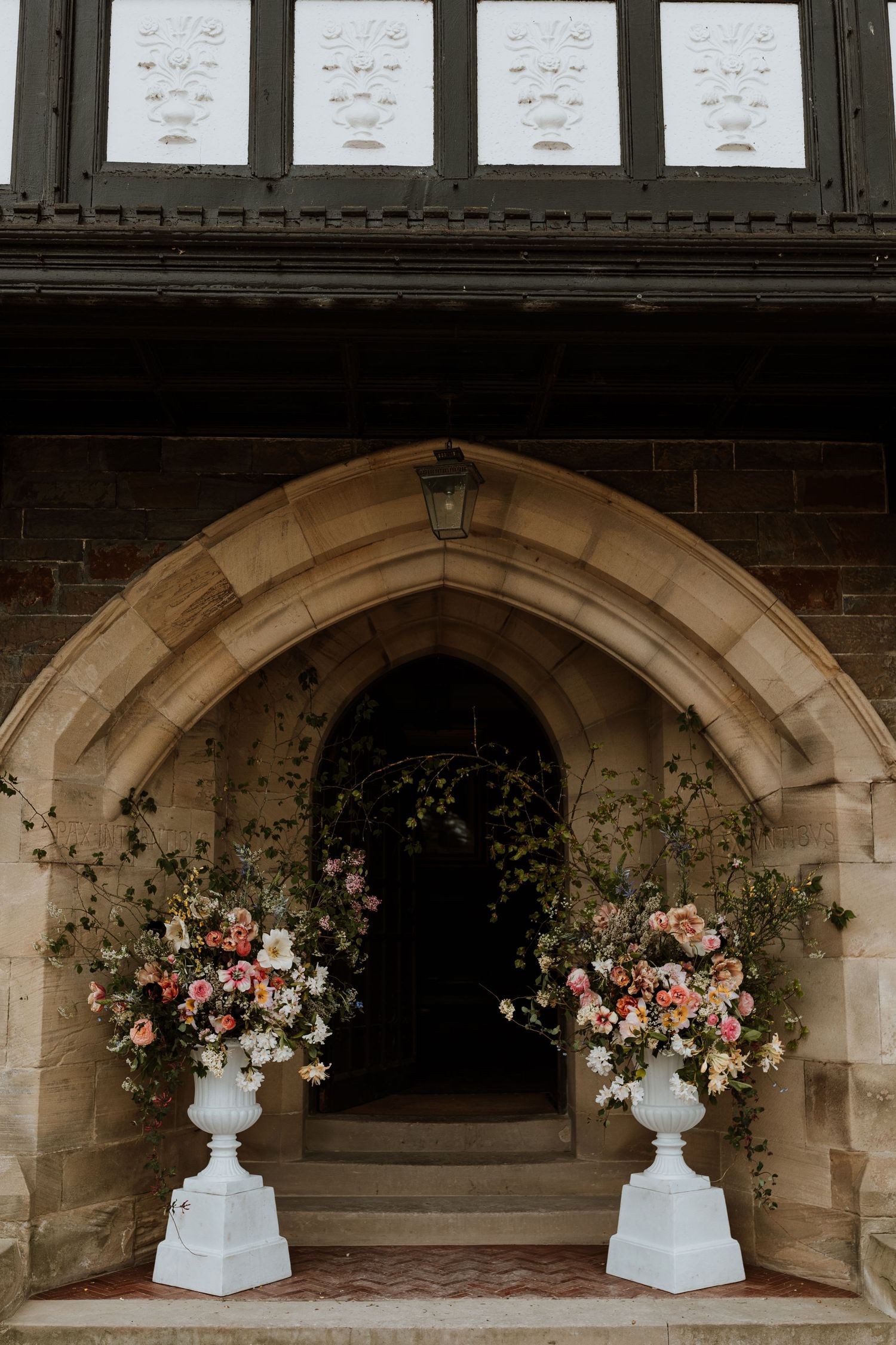 A series of ornate stone archways decorated with elegant floral arrangements in white urns for a wedding or event.