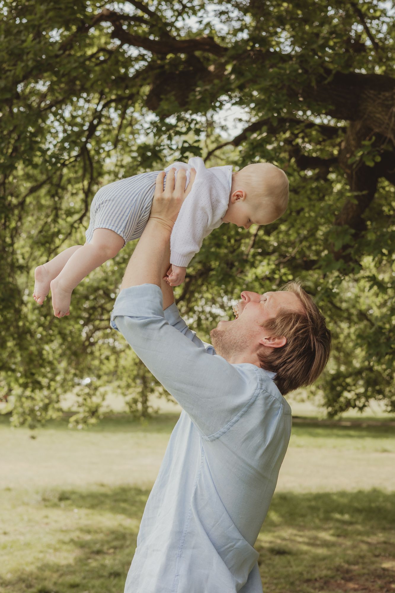 dad throws toddler in the air and laughs on Wandsworth common