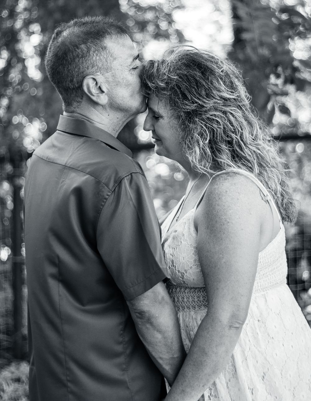 A romantic black and white outdoor portrait of a tender moment between a couple embracing in nature.