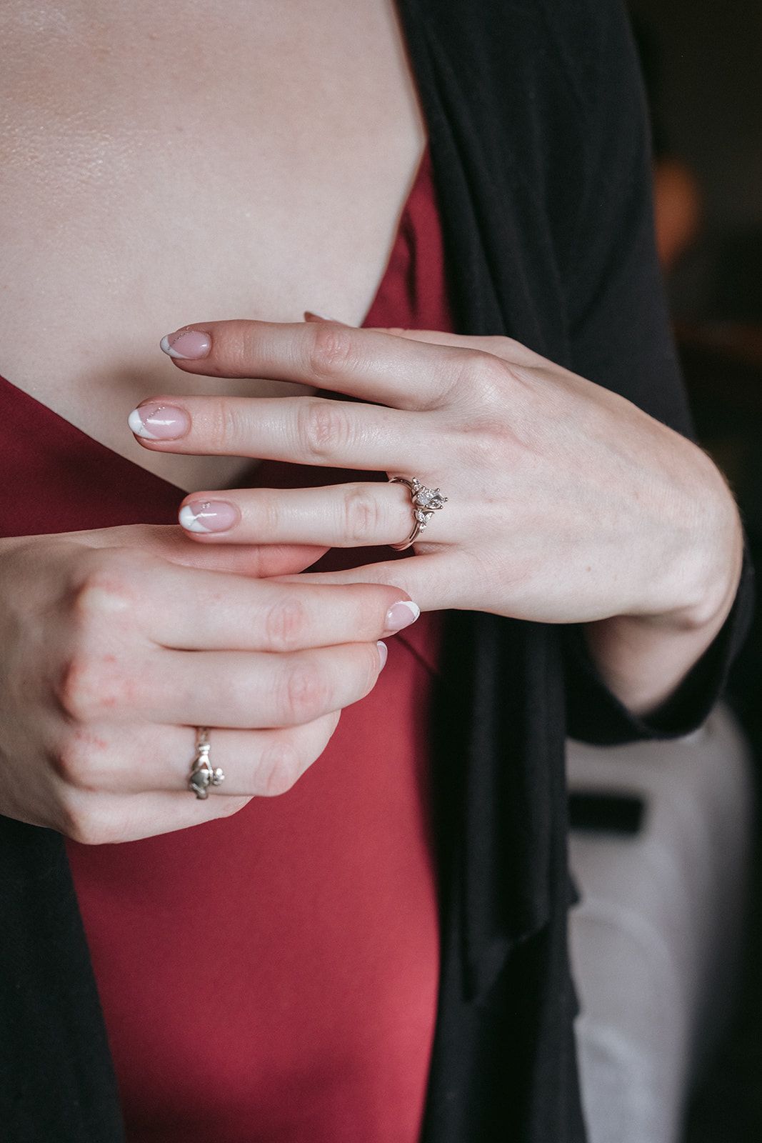 Close-up of hands showing ring details against a red dress and black cardigan.