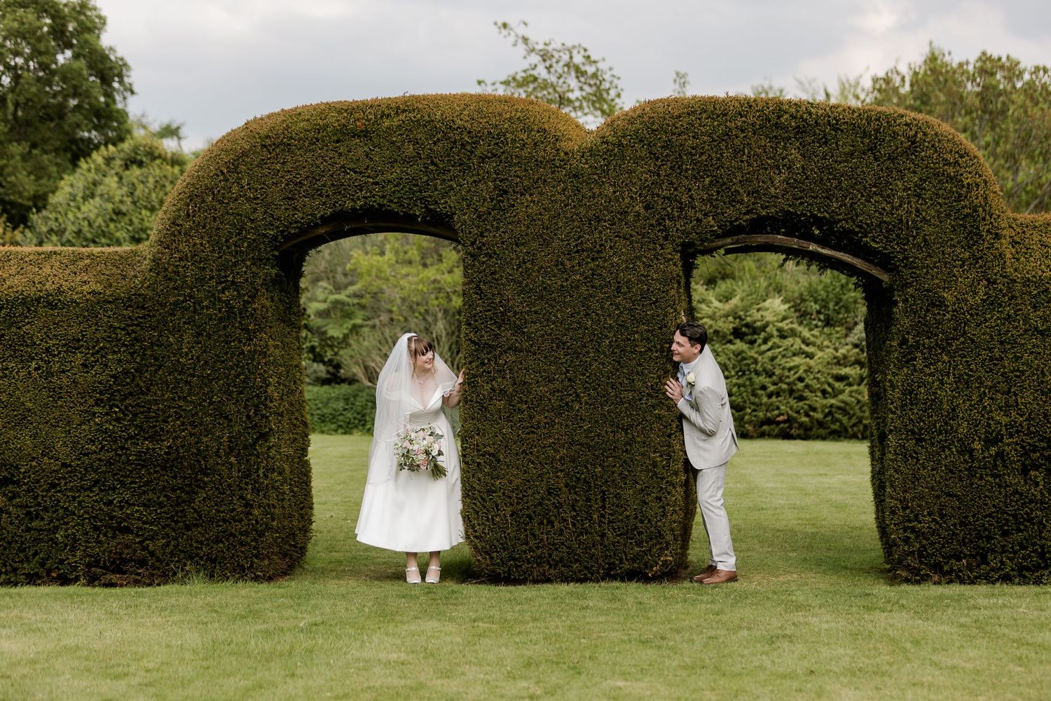 Wedding couple peeking through the hedges at Barnett Hill Hotel