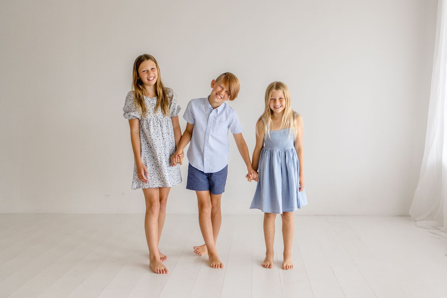 Three people in coordinating blue and white outfits pose together against a white studio background.