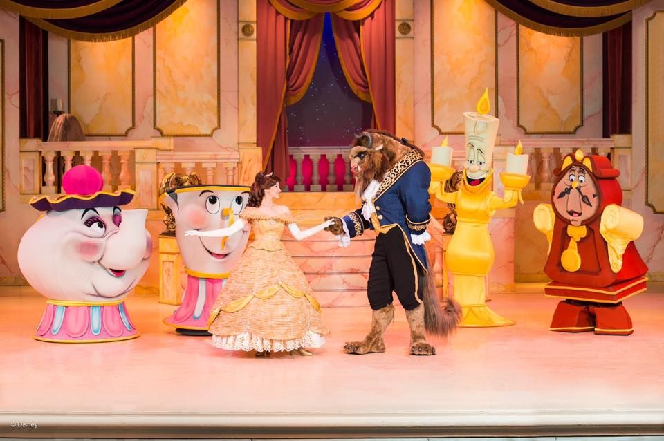 Musical stage show performance featuring animated character costumes and ornate palace backdrop.