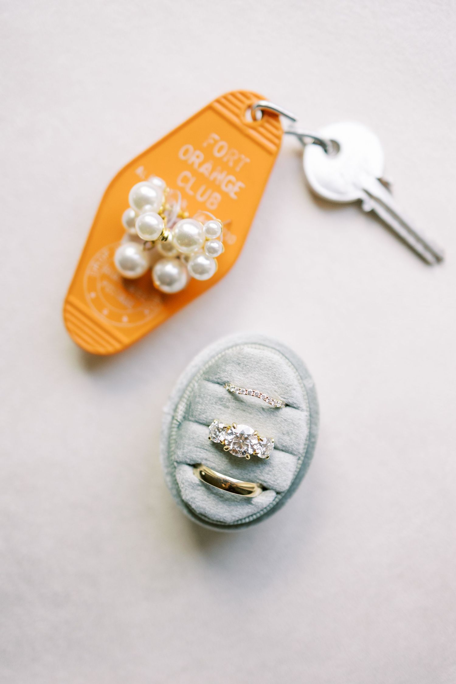 Step by step photos showing the creative process of assembling delicate pearl and rhinestone embellishments on mint and orange discs.