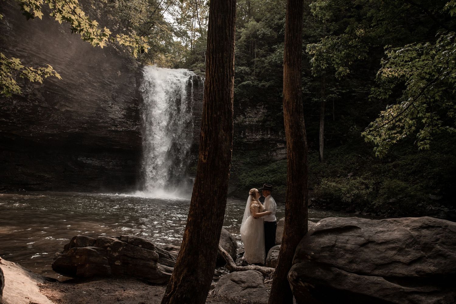 newly weds have their wedding photographer capture a wedding portrait in front of a waterfall at cloudland state park in georgia