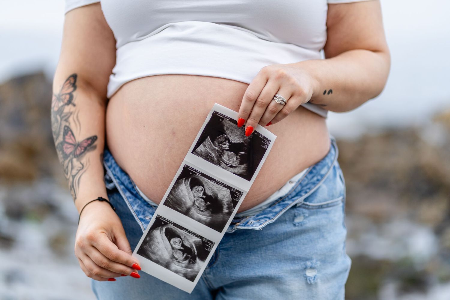 A woman in denim holds an ultrasound photo while showing her pregnant belly in a series of intimate maternity portraits.